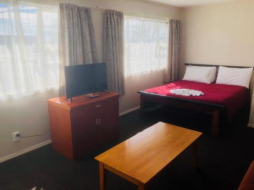 a room with a bed with a television and a table at Gateway International Motel in Rotorua