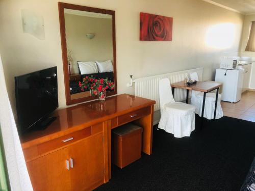 a room with a dresser with a tv and a mirror at Gateway International Motel in Rotorua