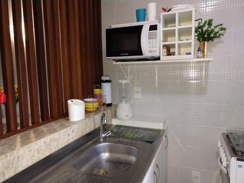 eine Küche mit Spüle und Mikrowelle in der Unterkunft Flat Winterwille Gravatá in Gravatá