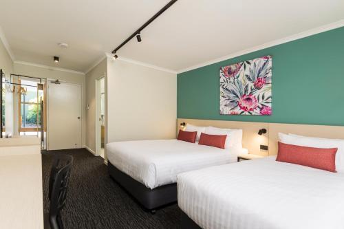 a hotel room with two beds and a painting on the wall at Nightcap At Balaclava Hotel in Cairns
