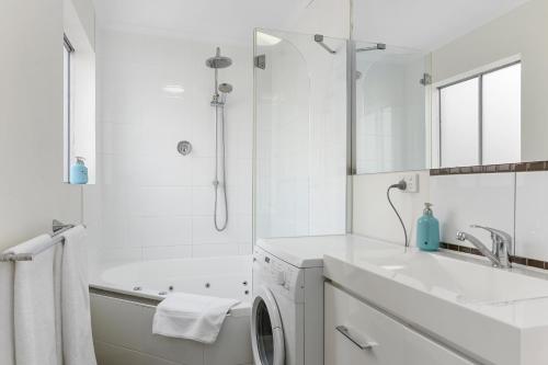 Trinity Hill Apartments في هوبارت: حمام ابيض مع مغسلة وغسالة ملابس