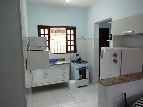 a kitchen with white cabinets and a white refrigerator at Vianna de Boracéia in Boracéia