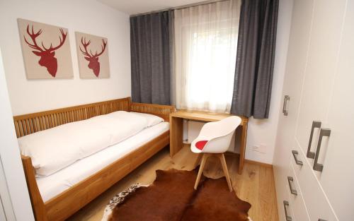 a bedroom with a bed and a desk and a chair at Au Réduit 412 in St. Moritz