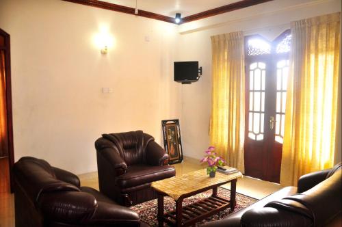 uma sala de estar com duas cadeiras de couro e uma mesa em Power Zone Guest House em Matale