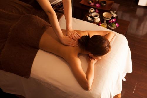 a woman laying on a bed with her hands on her back at Loisir Spa Tower Naha in Naha