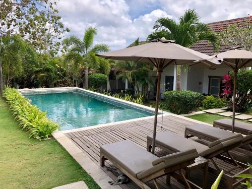 a swimming pool with two chairs and an umbrella at Casa Asia in Uluwatu