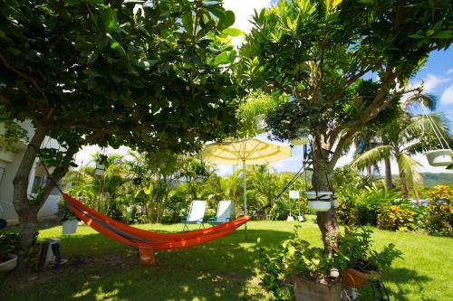 a hammock in a garden with two chairs and an umbrella at Sun Green Resort Hotel Ishigaki in Ishigaki Island