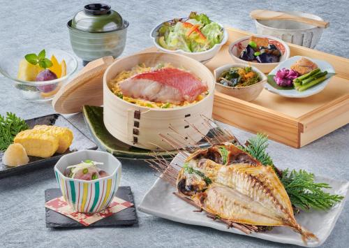 伊東市にあるセブンシーズホテル 伊東の魚やその他の料理が載った食事のトレイが置かれたテーブル