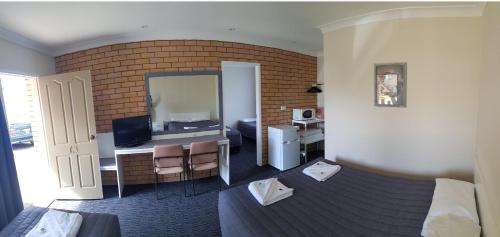 a hotel room with a bedroom with a bed and a desk at Goldfields Motel in Blayney