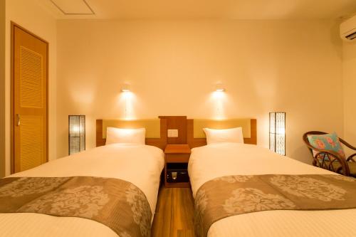 a room with two beds with lights on the wall at Sun Green Resort Hotel Ishigaki in Ishigaki Island