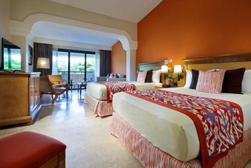 a hotel room with two beds and a television at Grand Palladium Colonial Resort & Spa - All Inclusive in Akumal