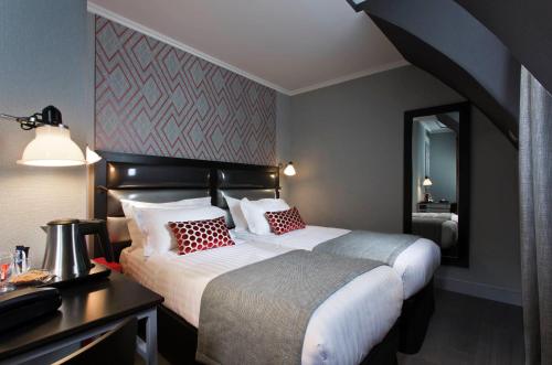 een slaapkamer met 2 bedden, een bureau en een spiegel bij Hôtel Garance in Parijs