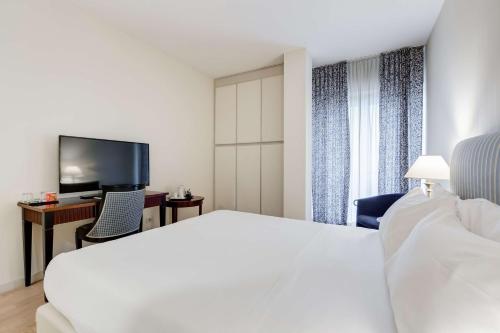 a hotel room with a white bed and a tv at Villa Maria Hotel & SPA in Francavilla al Mare