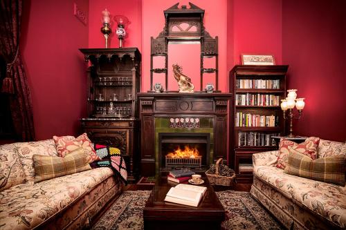 a living room with a fireplace and a red wall at Kurrara Historic Guest House in Katoomba
