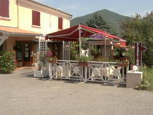a restaurant with a table and a fence with flowers at Logis Hotel Le Relais du Serre in Dieulefit