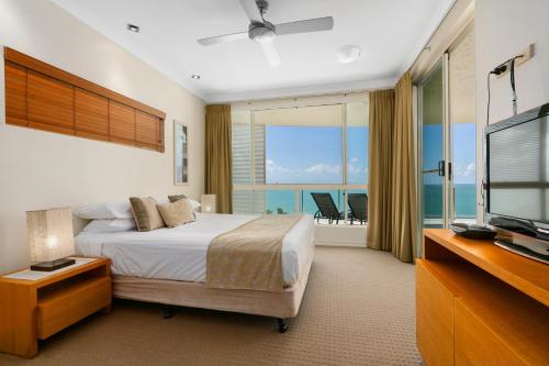 Bellevue At Trinity Beach في شاطئ ترينيتي: غرفة نوم بسرير وتلفزيون وشرفة
