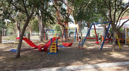 un parco giochi con un mucchio di altalene e alberi di Camping Drepanos a Igoumenítsa