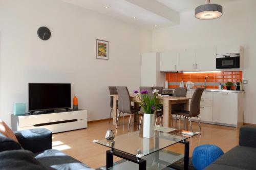Una sala de estar con una mesa y una cocina. en GE Apartments, en Praga