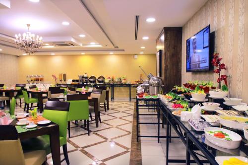 um restaurante com mesas longas e cadeiras verdes em City Rose Hotel Suites em Amã