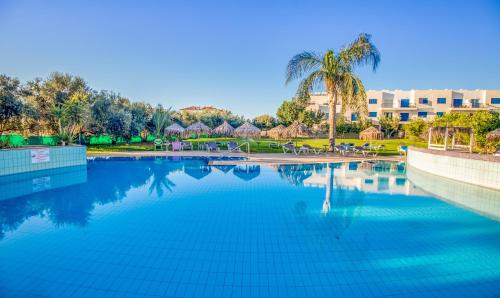 a large swimming pool with a palm tree and a building at Captain Karas Holidays Apartments in Protaras