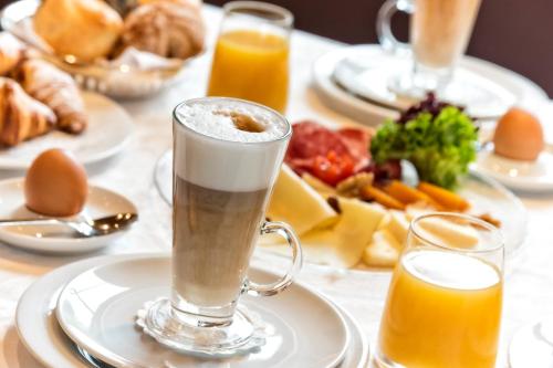 a table with plates of food and glasses of orange juice at Hotel Post - OlangCard included in Valdaora