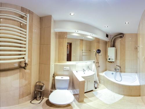 La salle de bains est pourvue de toilettes, d'un lavabo et d'une baignoire. dans l'établissement Batory Apartament, à Chorzów