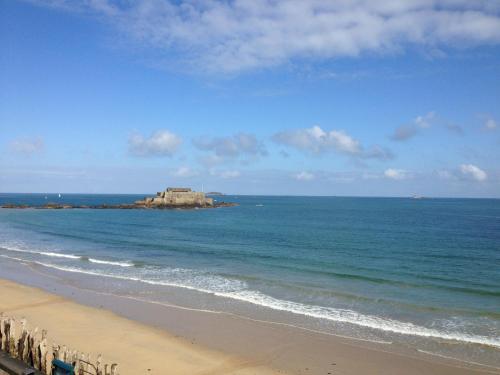 une plage avec une maison sur une île dans l'océan dans l'établissement La Galissonnière, à Saint-Malo