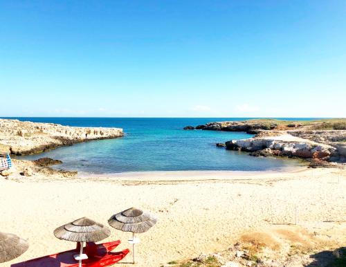 two people sitting under umbrellas on a beach at My Monopoli - Casa dei Fiori "Iris" Cala Paradiso in Monopoli