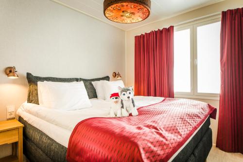 two stuffed animals sitting on a bed in a bedroom at Santa Claus Holiday Village in Rovaniemi