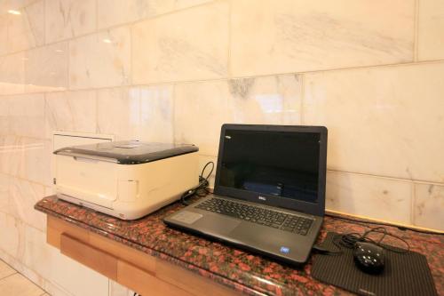 a laptop computer sitting on a counter next to a printer at Smile Hotel Tokyo Ayase Ekimae in Tokyo