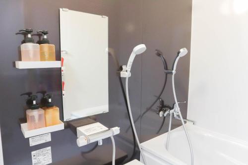 uma casa de banho com um espelho e um lavatório branco em Ryukyu Tabikan #3F em Ginowan