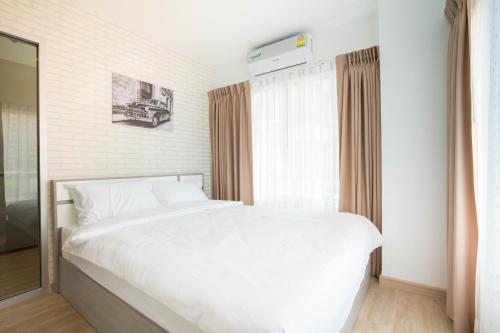 a bedroom with a white bed and a window at The Lux Ladprao 10 in Bangkok