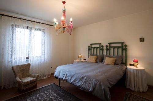 1 dormitorio con 1 cama con lámpara de araña y silla en La Stalla, en Cepagatti