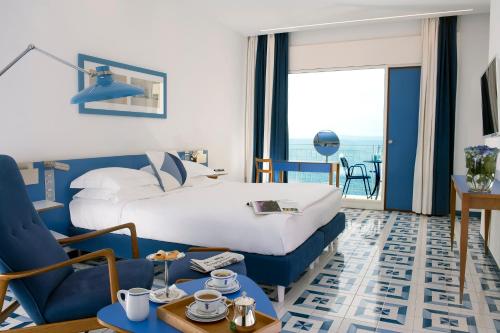 a hotel room with a king sized bed and a view of the ocean at Parco dei Principi in Sorrento