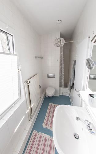 a white bathroom with a sink and a toilet at Lotsenkoje in Cuxhaven