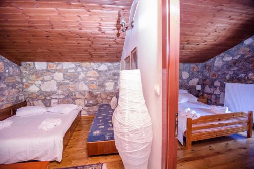 a bedroom with two beds and a stone wall at Stonehouse 2 Bedroom Chalet on Olympus Amazing View in Pétra