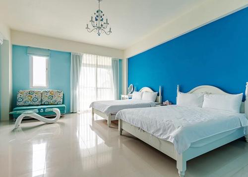 um quarto com 2 camas e uma parede azul em Eik Forest B&B em Taitung City