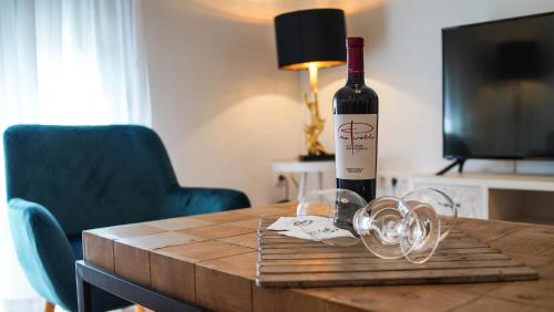 una botella de vino sentada en una mesa con copas en Apartamentos Soho Boutique Plaza Mayor Caceres en Cáceres