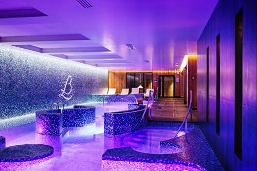 - un hall d'accueil avec éclairage violet et tabourets de bar dans l'établissement Relais Bernard Loiseau, à Saulieu