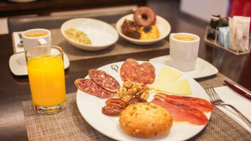a plate of breakfast food and a glass of orange juice at Soho Boutique Casa Don Fernando in Cáceres