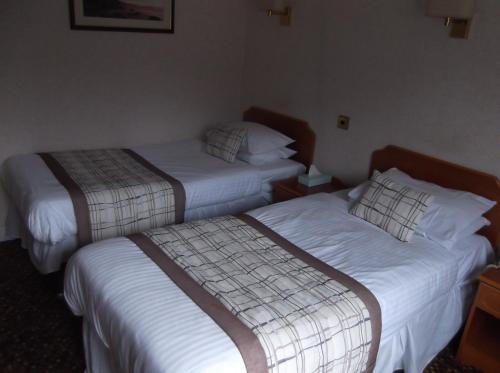 two beds in a hotel room with white sheets at Arrochar Hotel 'A Bespoke Hotel' in Arrochar