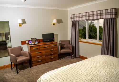 um quarto com uma cama e 2 cadeiras e uma televisão em Tyndrum Lodges em Tyndrum