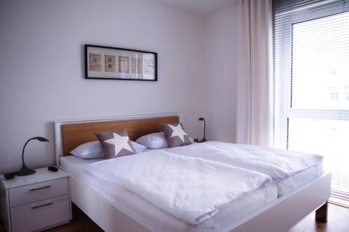 a white bedroom with a white bed and a window at Fewo an der Kulturbäckerei in Lüneburg