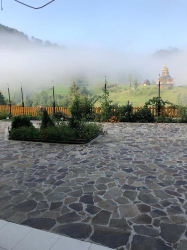 a stone courtyard with a fence and a mountain at Privatna Sadiba Chalet in Oryavchyk