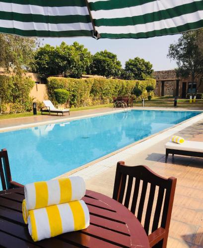 a swimming pool with two chairs and a table and an umbrella at Beautiful Apartments at Tarudhan Valley Golf Resort, Manesar in Gurgaon