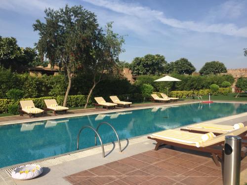 una piscina con tumbonas y una mesa en Beautiful Apartments at Tarudhan Valley Golf Resort, Manesar, en Gurgaon