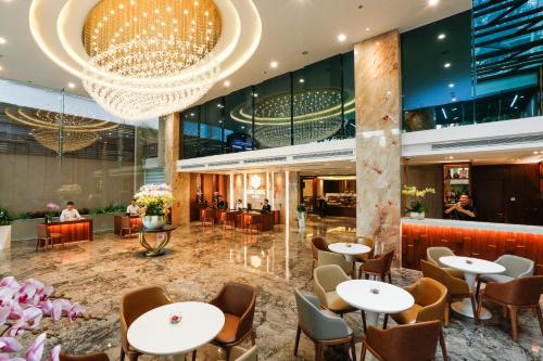 Orchids Saigon Hotel في مدينة هوشي منه: لوبي الفندق به طاولات وكراسي وثريا