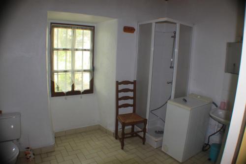 une salle de bain avec des toilettes, une chaise et une fenêtre dans l'établissement les écureuils, à Saint-Priest