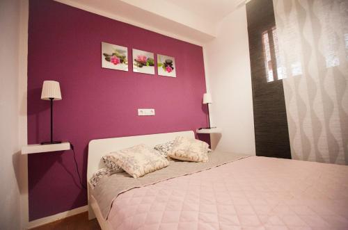 アデへにあるCozy Apartment in Costa Adeje,Torviscas playaの紫の壁のベッドルーム(ベッド付)