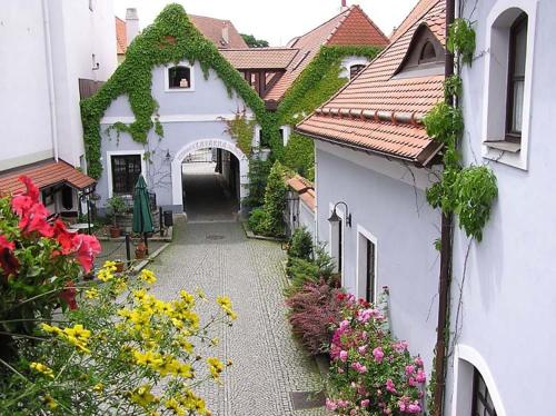 an alley between two white buildings with flowers at Penzion a restaurace U Míšků in Třeboň